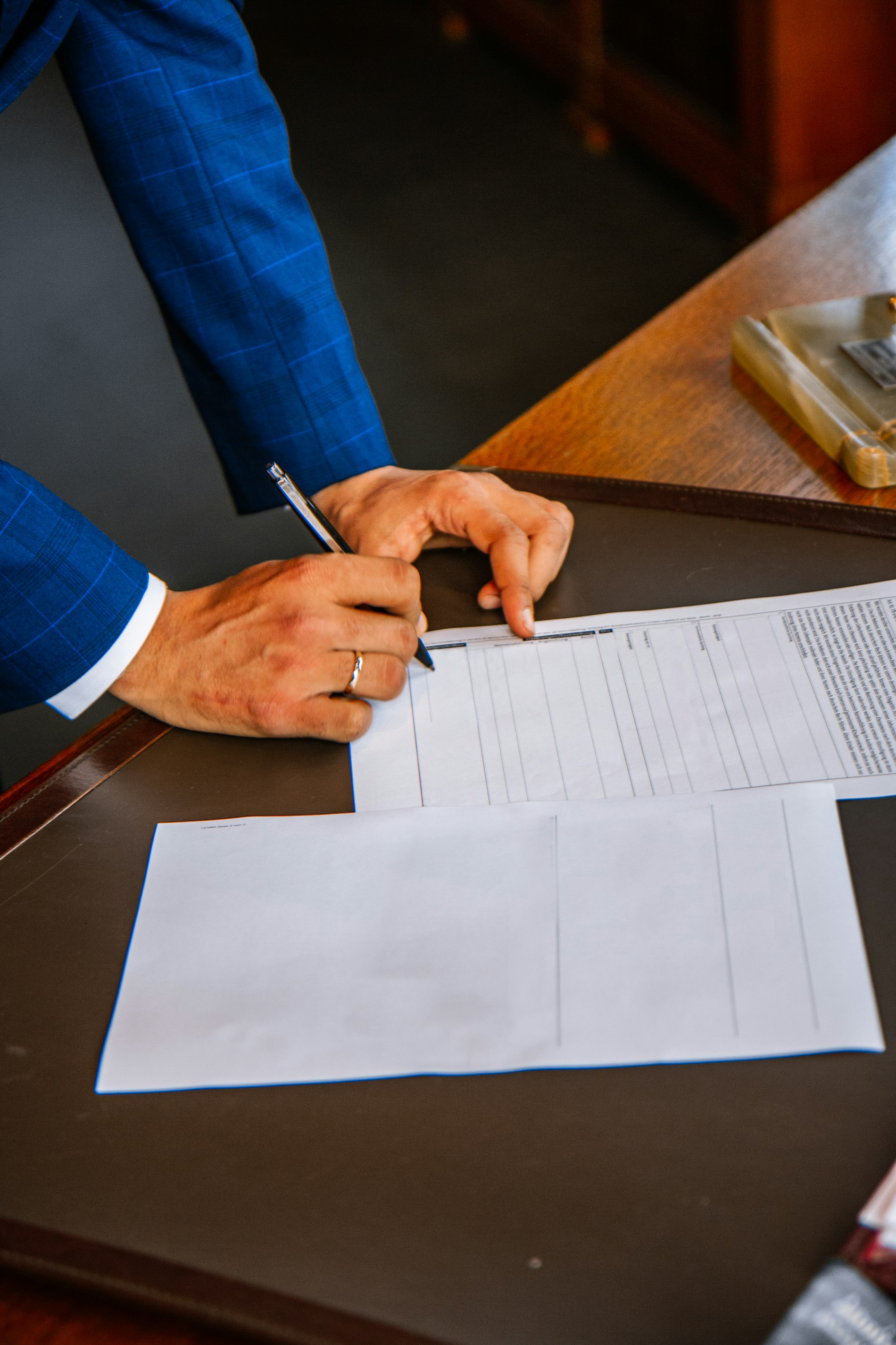 Signature d'un contrat au stylo sur un bureau en cuir foncé, cadre solide